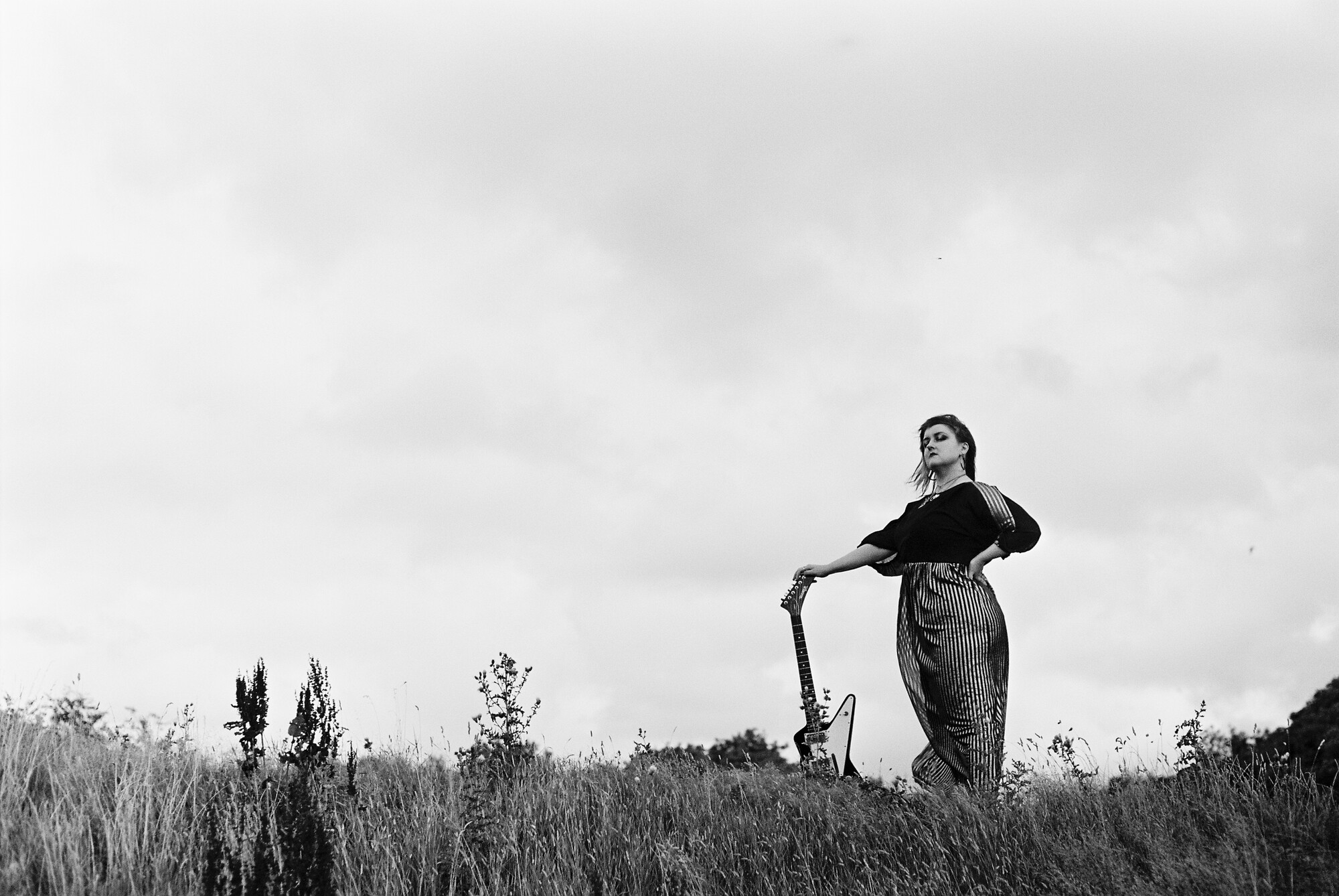 Von Dodds standing outdoors with her guitar, photographed by Carey Whitfield